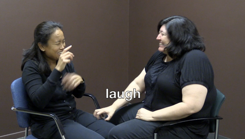 Two women laughing and signing.