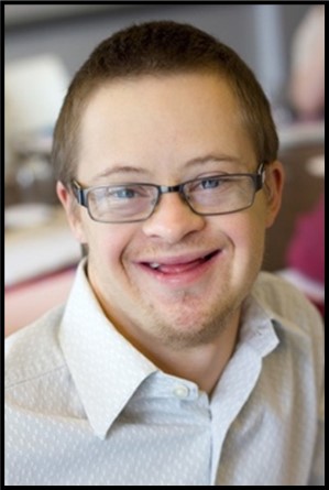 {Image: A man with glasses is smiling and looking very happy.  He has short brown hair and is wearing a collared shirt. He has features of a person with down syndrome}.{Image: A man with glasses is smiling and looking very happy.  He has short brown hair and is wearing a collared shirt. He has features of a person with down syndrome}.