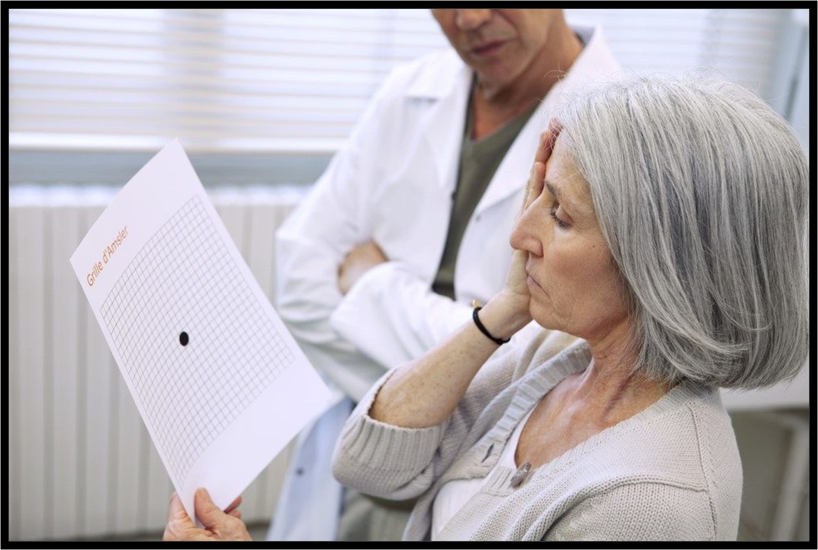 Image: A woman with gray hair looks at a sheet of paper with lines and a circle as she covers her right eye with her right hand.  Beside her there is a person wearing a white lab coat, also looking at the paper. 